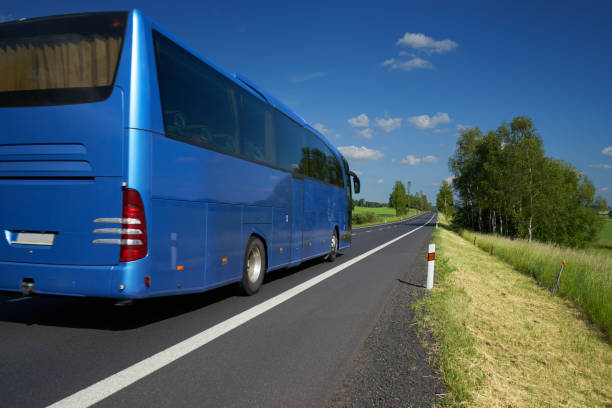 Blue bus traveling on asphalt road in a rural landscape